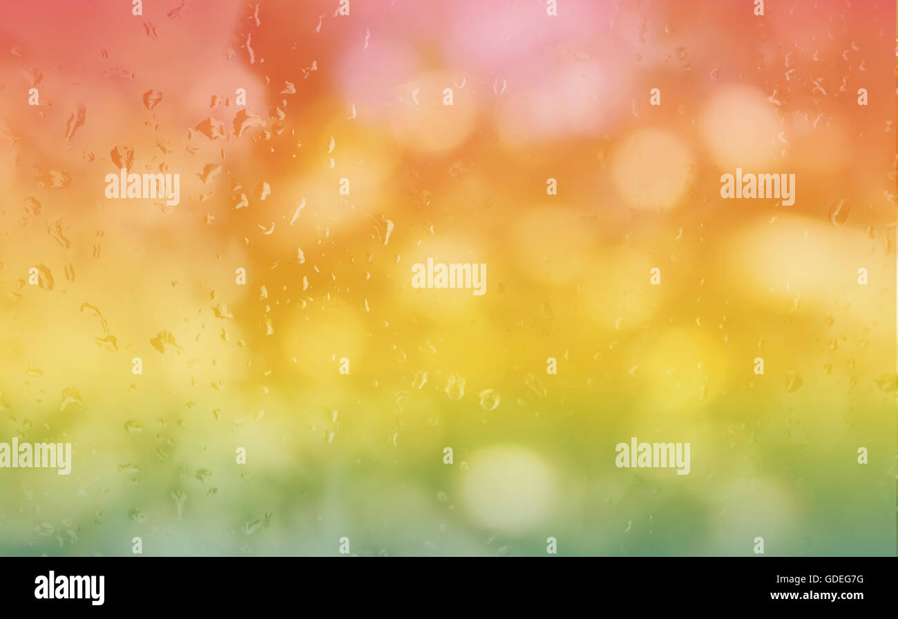 Abstract sfondo sfocato caduta di pioggia su vetro specchietto nella fresca estate colorato arancione rosa e verde bokeh di fondo Foto Stock