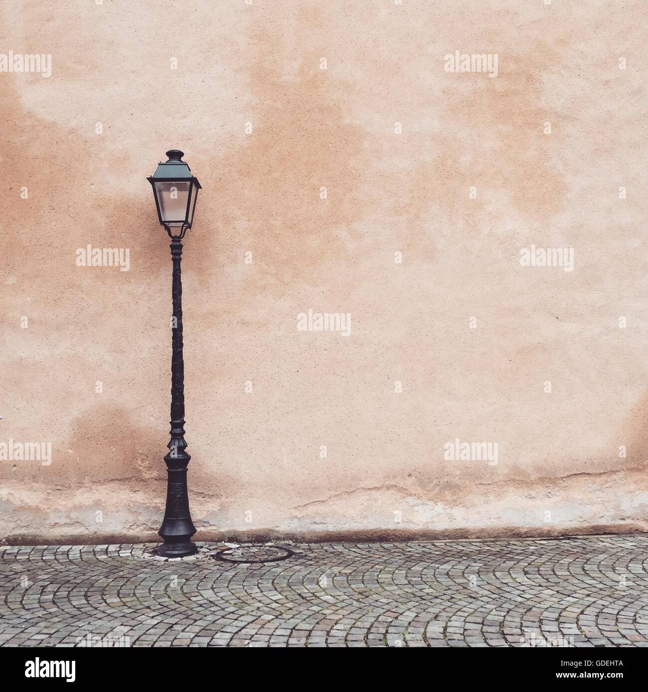 Lanterna di strada in strada di ciottoli da parete rosa Foto Stock