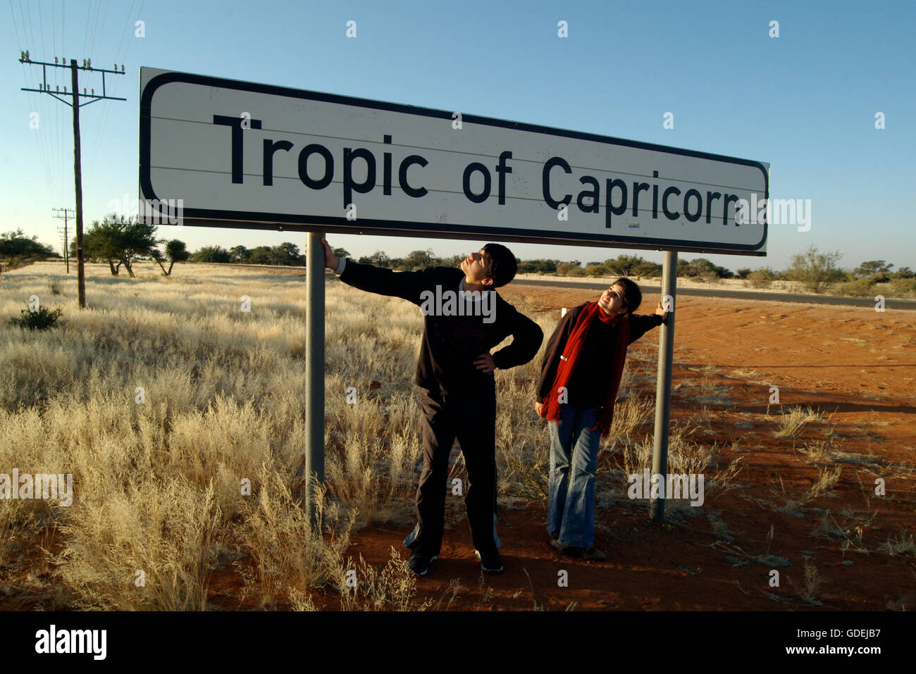 Ragazzo adolescente e una ragazza in piedi sotto il Tropico del Capricorno segno, Namibia Foto Stock