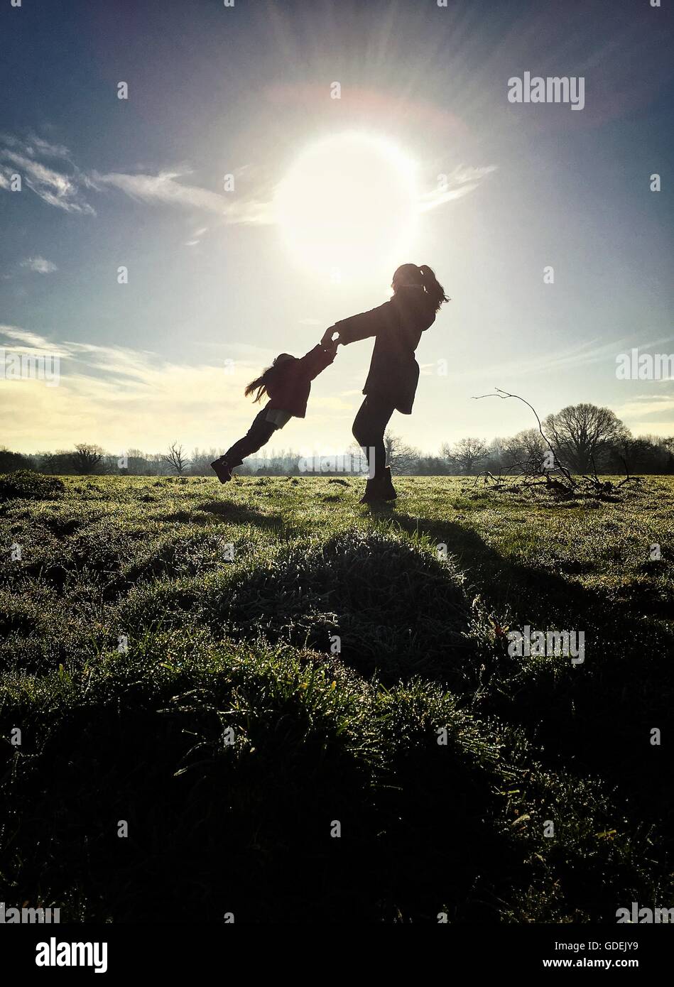 Silhouette di madre figlia oscillante nel campo Foto Stock