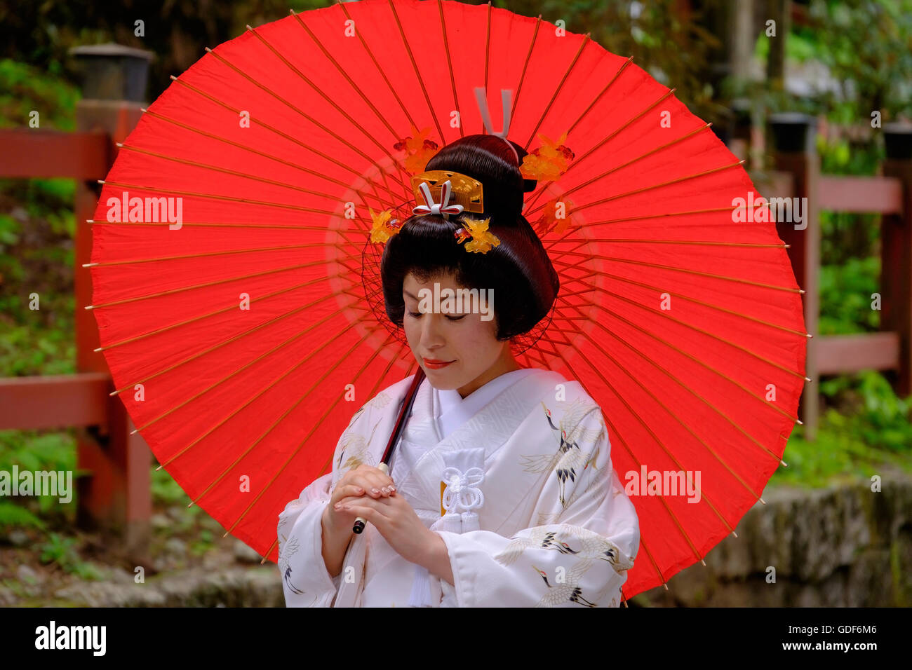 Una donna giapponese nel matrimonio tradizionale costume con un ombrellone rosso. Foto Stock