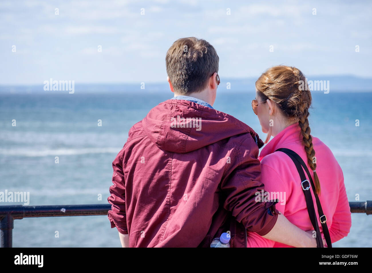 Un giovane uomo e donna che guarda il mare da un porto. Foto Stock
