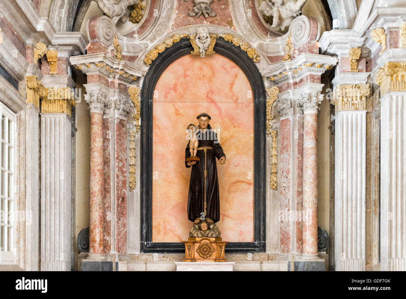 Cappella della Statua di Sant'Antonio Lisbona Portogallo // LISBONA, Portogallo — la Cappella di Sant'Antonio, situata all'interno del Monastero di São Vicente de Fora, è tradizionalmente ritenuta il luogo in cui Sant'Antonio fu internato mentre serviva come canonico regolare di Sant'Agostino. Completata nel 1740, la cappella si distingue per la sua elaborata decorazione in marmo policromo che esemplifica l'artigianato barocco portoghese. Il monastero circostante, costruito nel XVII secolo, si erge come uno dei monumenti religiosi più significativi di Lisbona nel quartiere di Alfama. São Vicente de Fora dispone di numerosi o Foto Stock