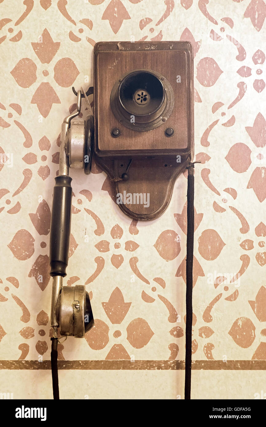 Il vecchio telefono con manovella è appeso alla parete decorazione Foto Stock