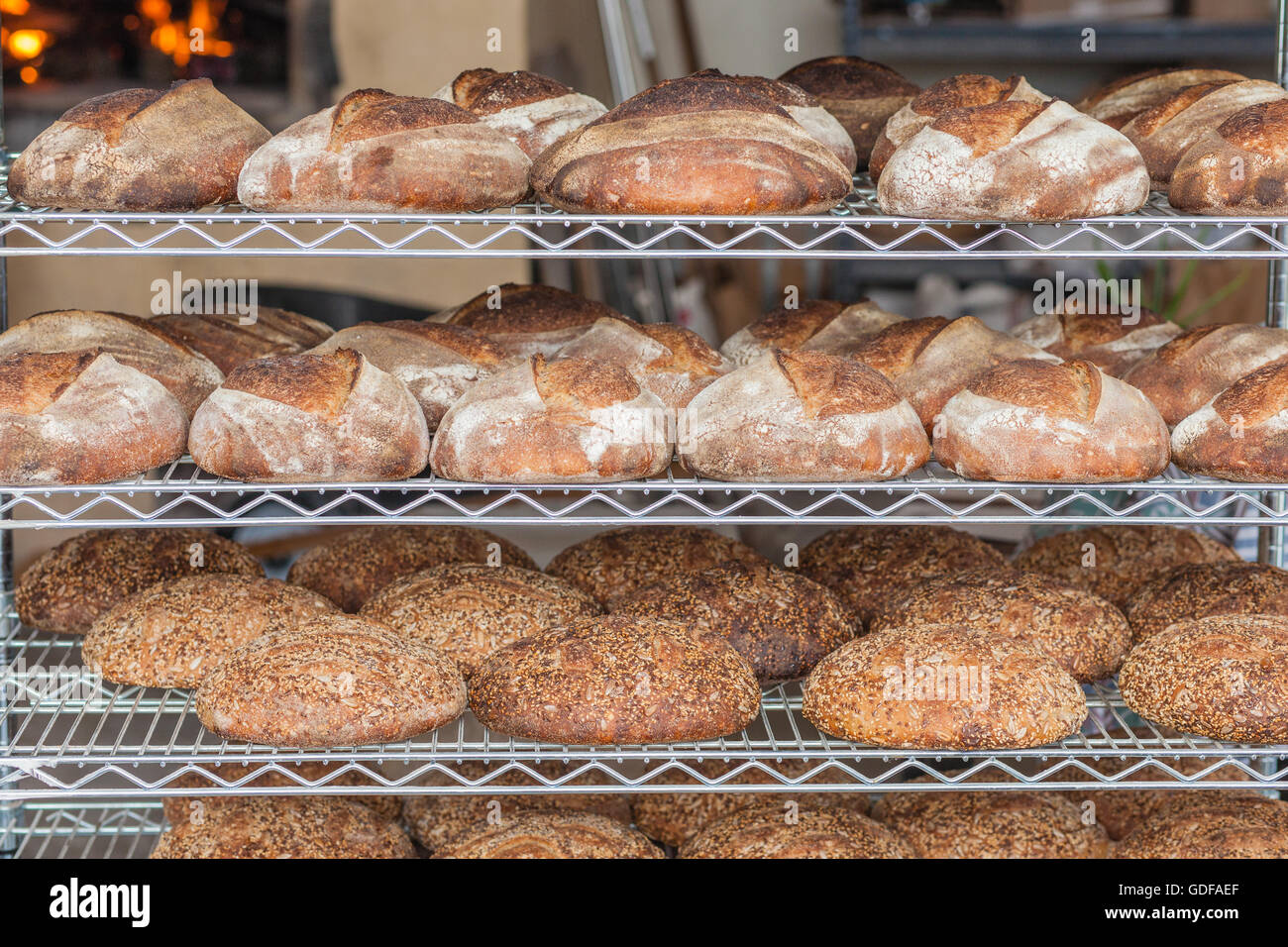 Pane appena sfornato a mano il pane biologico il raffreddamento in una pasticceria Foto Stock