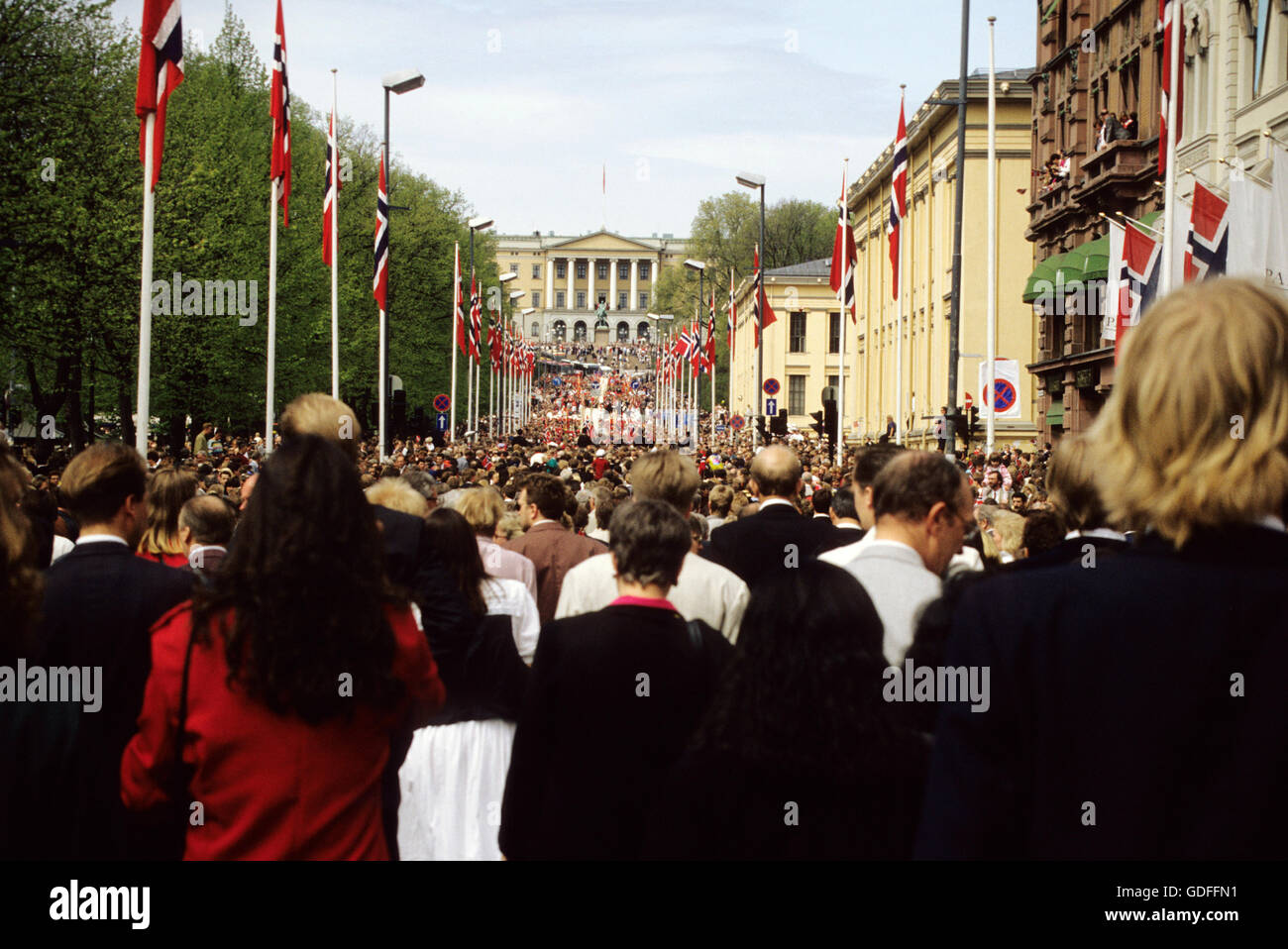 La gente in costume in parata verso il castello alla fine della strada principale Karl Johan Foto Stock