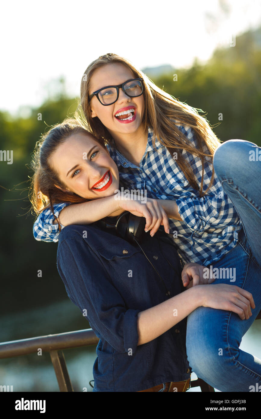 Amicizia, svago, estate e concetto di persone - due giocosi giovani donne divertimento all'aperto alla luce del tramonto Foto Stock