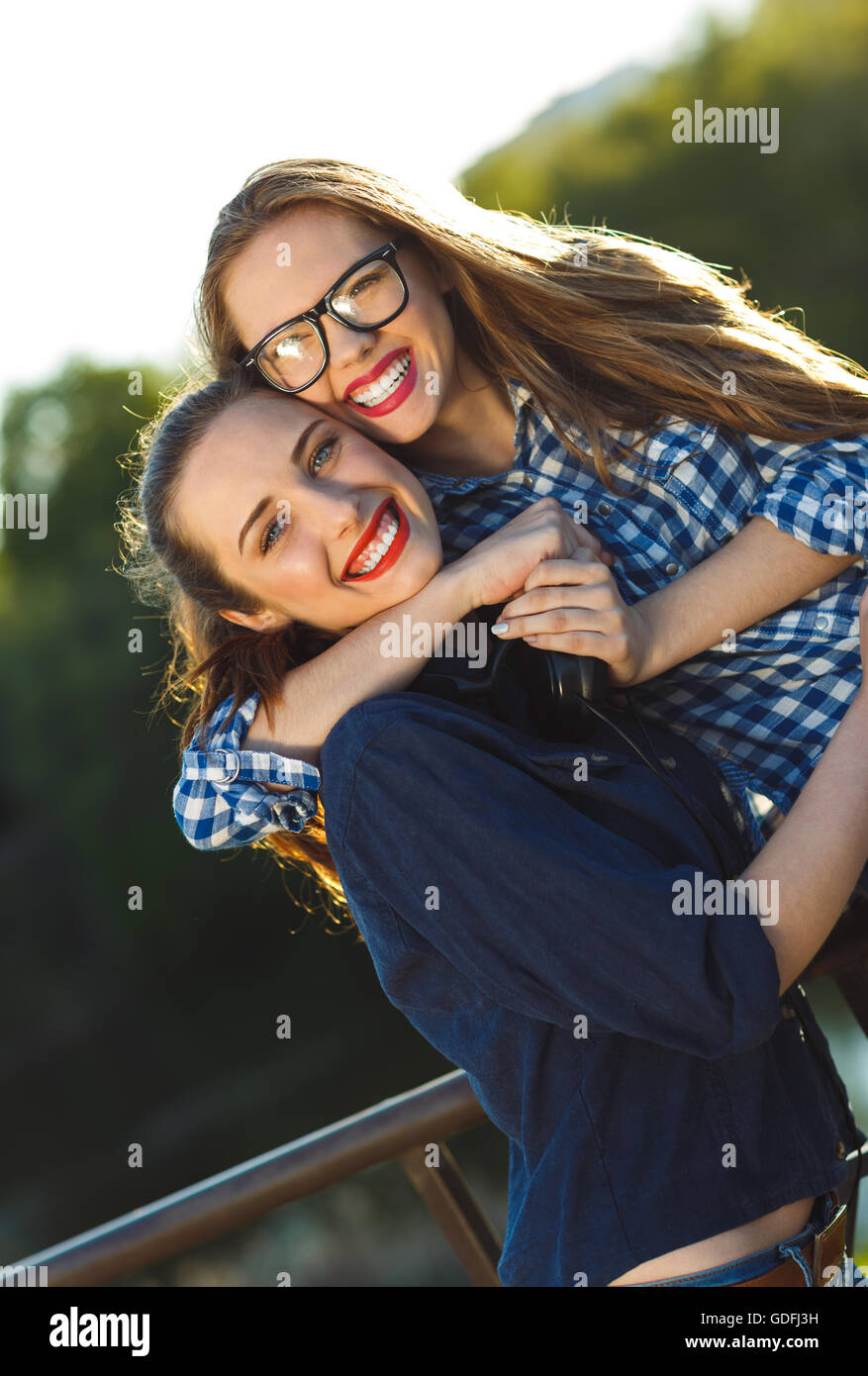 Amicizia, svago, estate e concetto di persone - due giocosi giovani donne divertimento all'aperto alla luce del tramonto Foto Stock