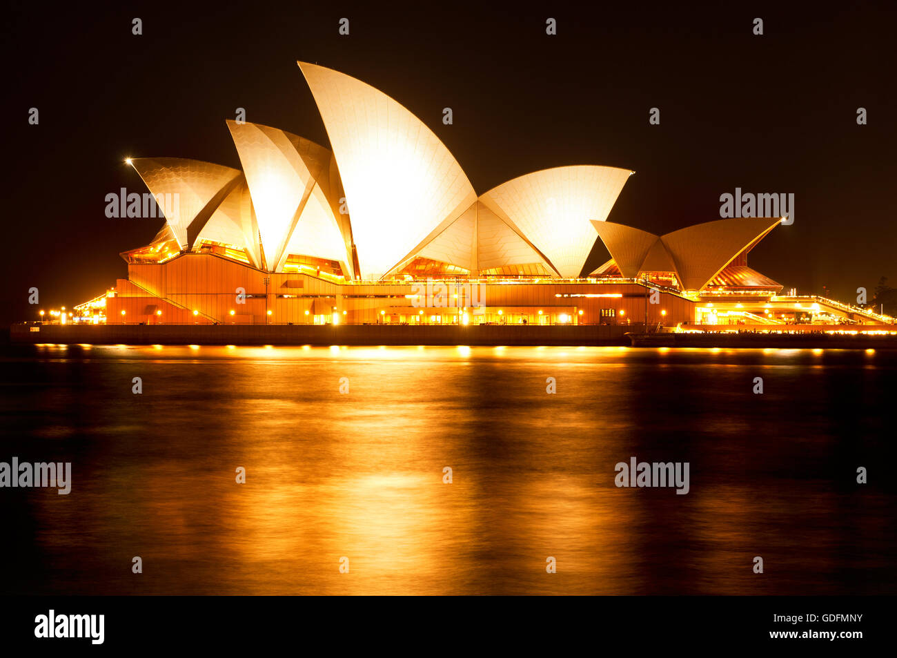 Accesa la Opera House di Sydney si riflette nell'acqua del porto. Foto Stock