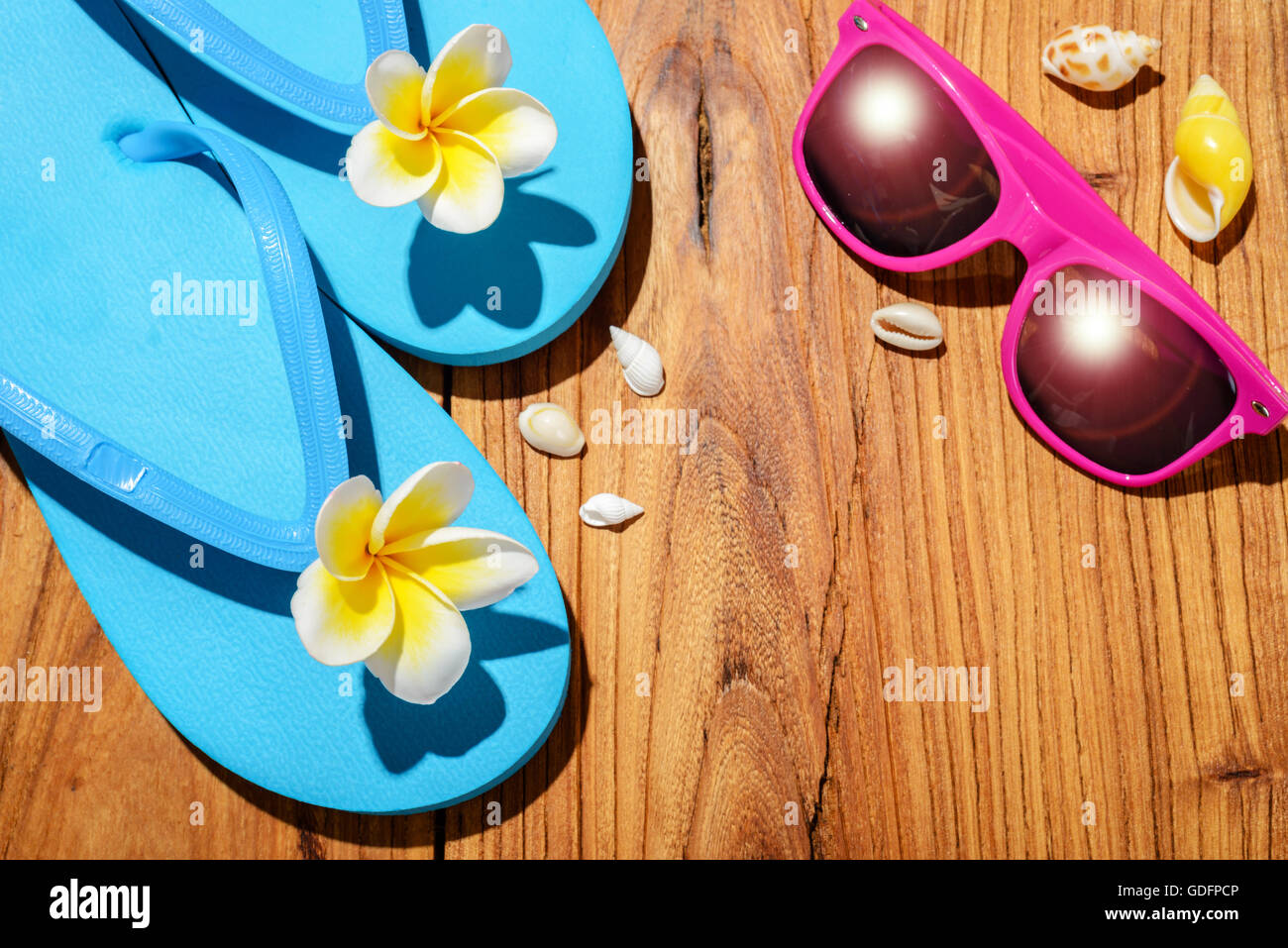 Il flip-flop e gli occhiali da sole sul pannello di legno Foto Stock