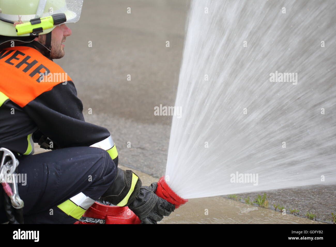 Un vigile del fuoco con monitor cannone ad acqua lancia di spruzzatura Foto Stock