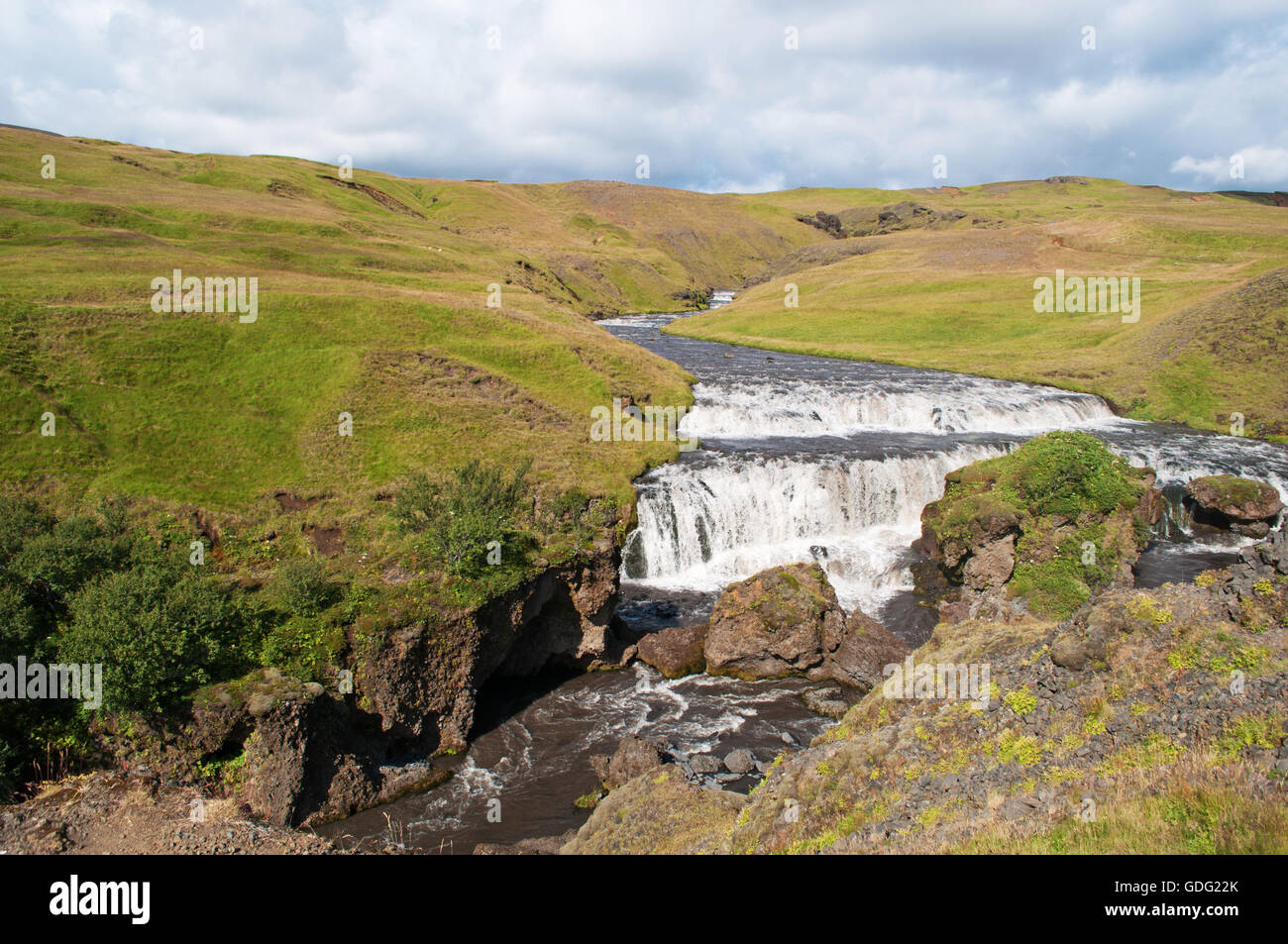 Islanda: vista della caduta superiore della cascata di Skogafoss e il fiume Skoga Foto Stock
