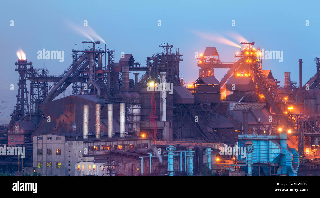 Stabilimento metallurgico di notte. Fabbrica di acciaio con fumaioli . Acciaierie e lavori di ferro. Industria pesante in Europa. Inquinamento atmosferico f Foto Stock