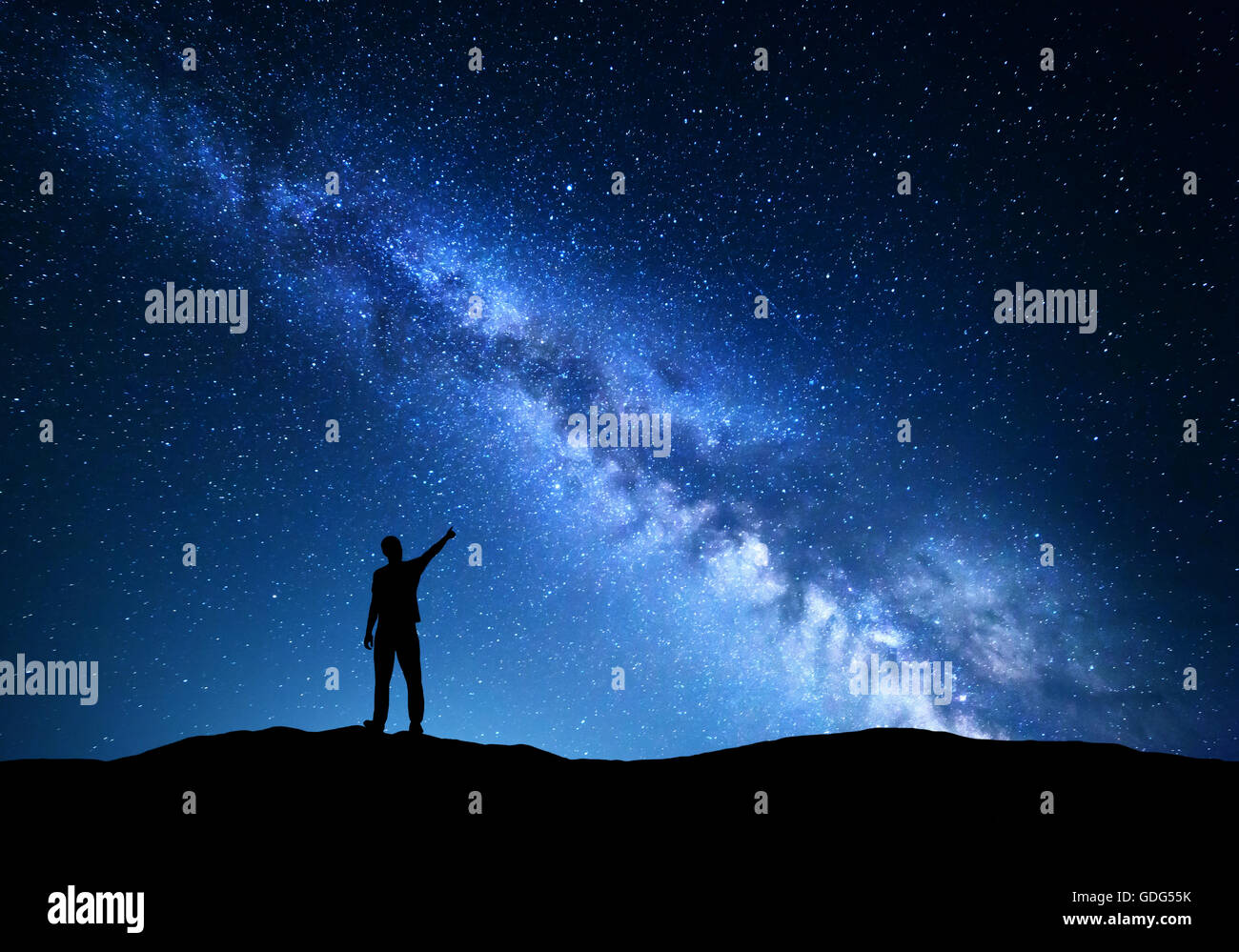 Via Lattea. Silhouette di un uomo in piedi puntando il dito nella notte cielo stellato sulla montagna. Colorato paesaggio notturno con beaut Foto Stock