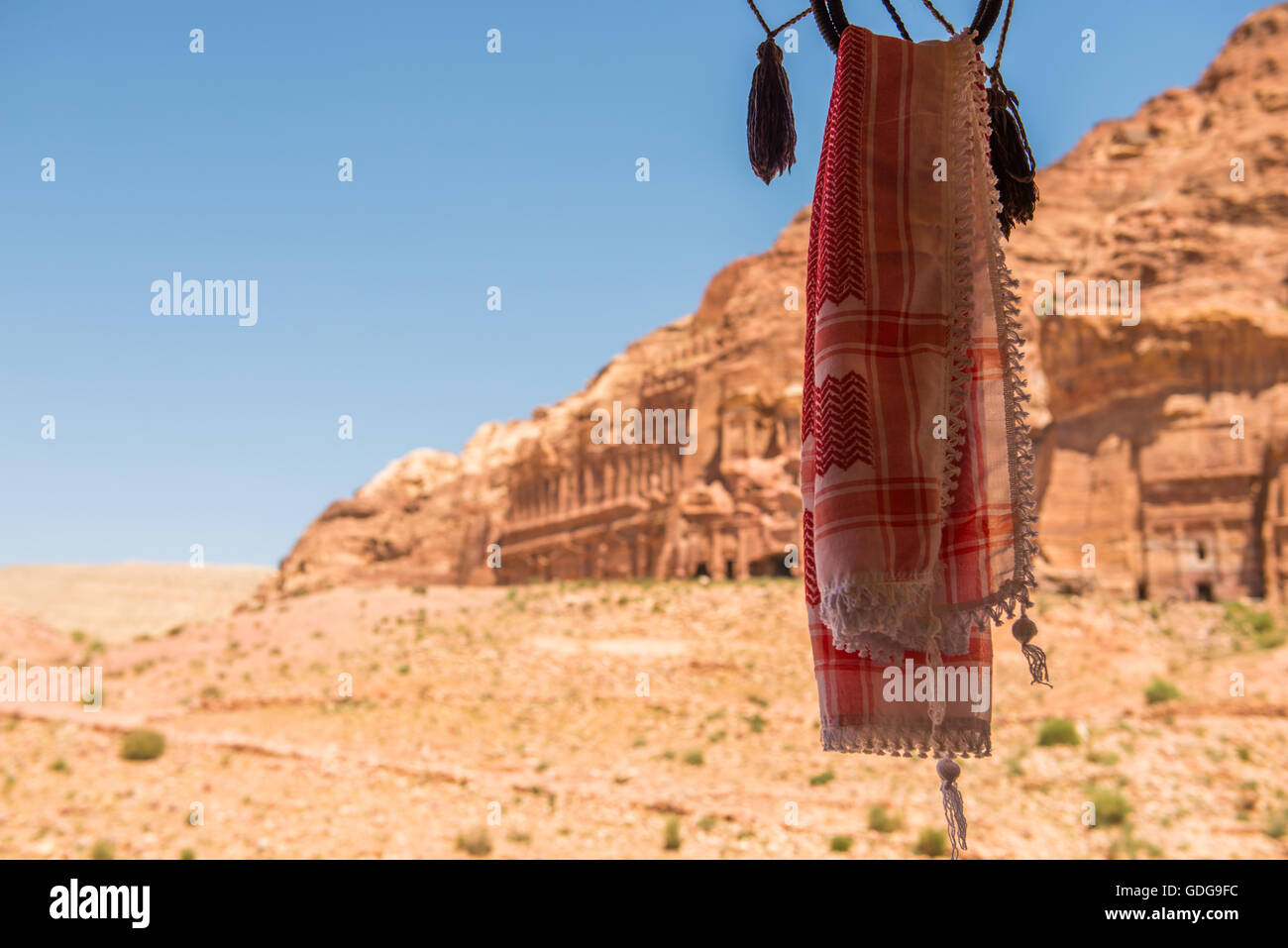 Un beduino tradizionale copricapo si blocca nella parte anteriore di Petra le massicce sculture Nabatean ed edifici in background. Foto Stock