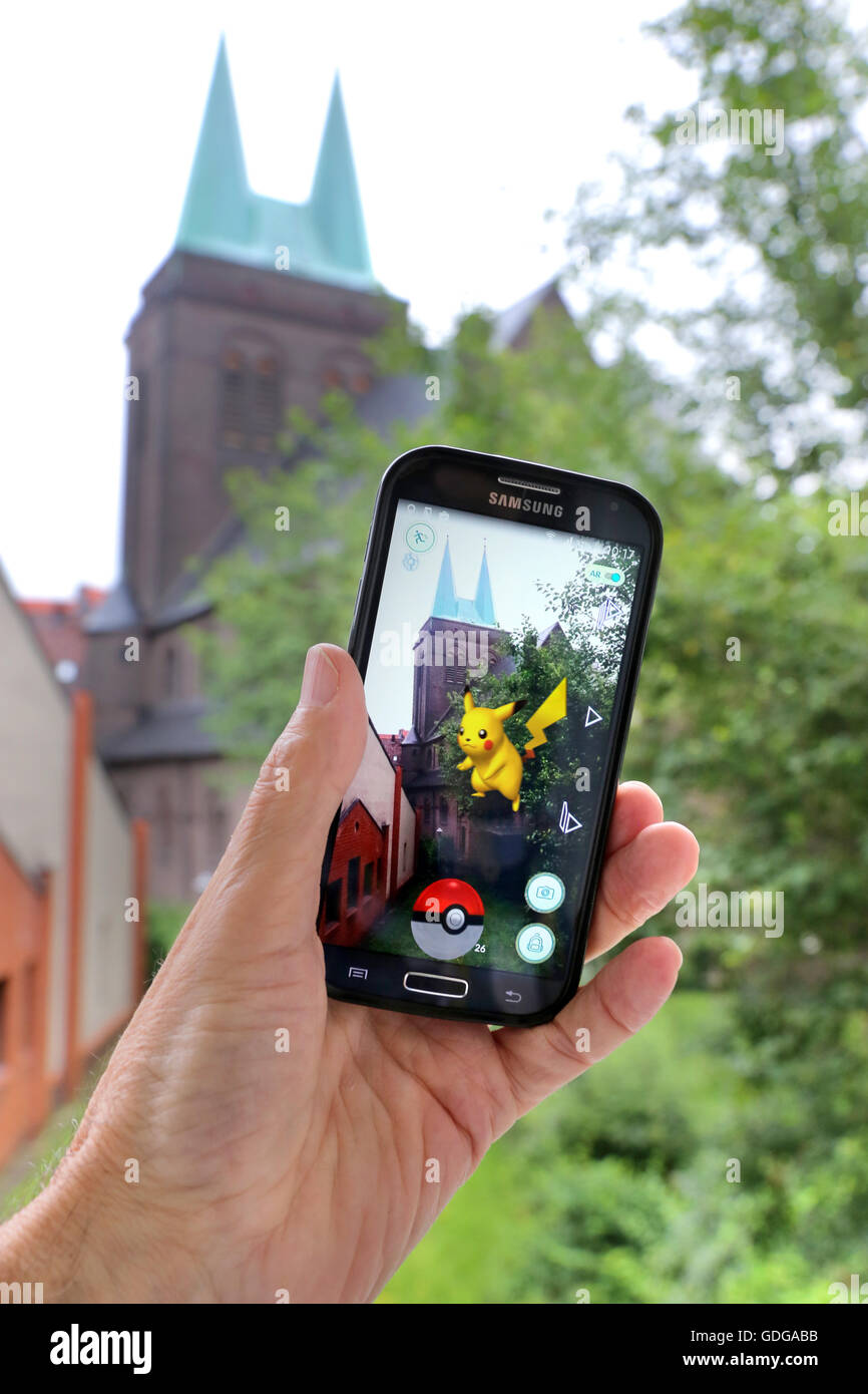 La versione tedesca dei più recenti videogiochi Pokémon 'go'. Pokemon mostro nel giardino della chiesa su uno smartphone di un giocatore. Dortmund, Germania, Luglio 17th.2016 Foto Stock