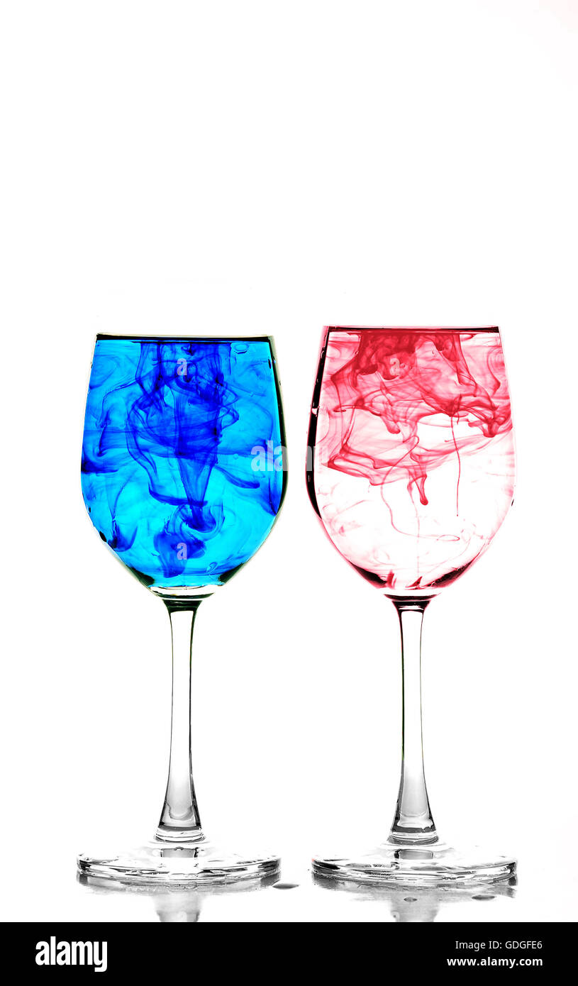 Due bicchieri di vino riempito con acqua e diffondere il rosso, il giallo e il blu inchiostro Foto Stock