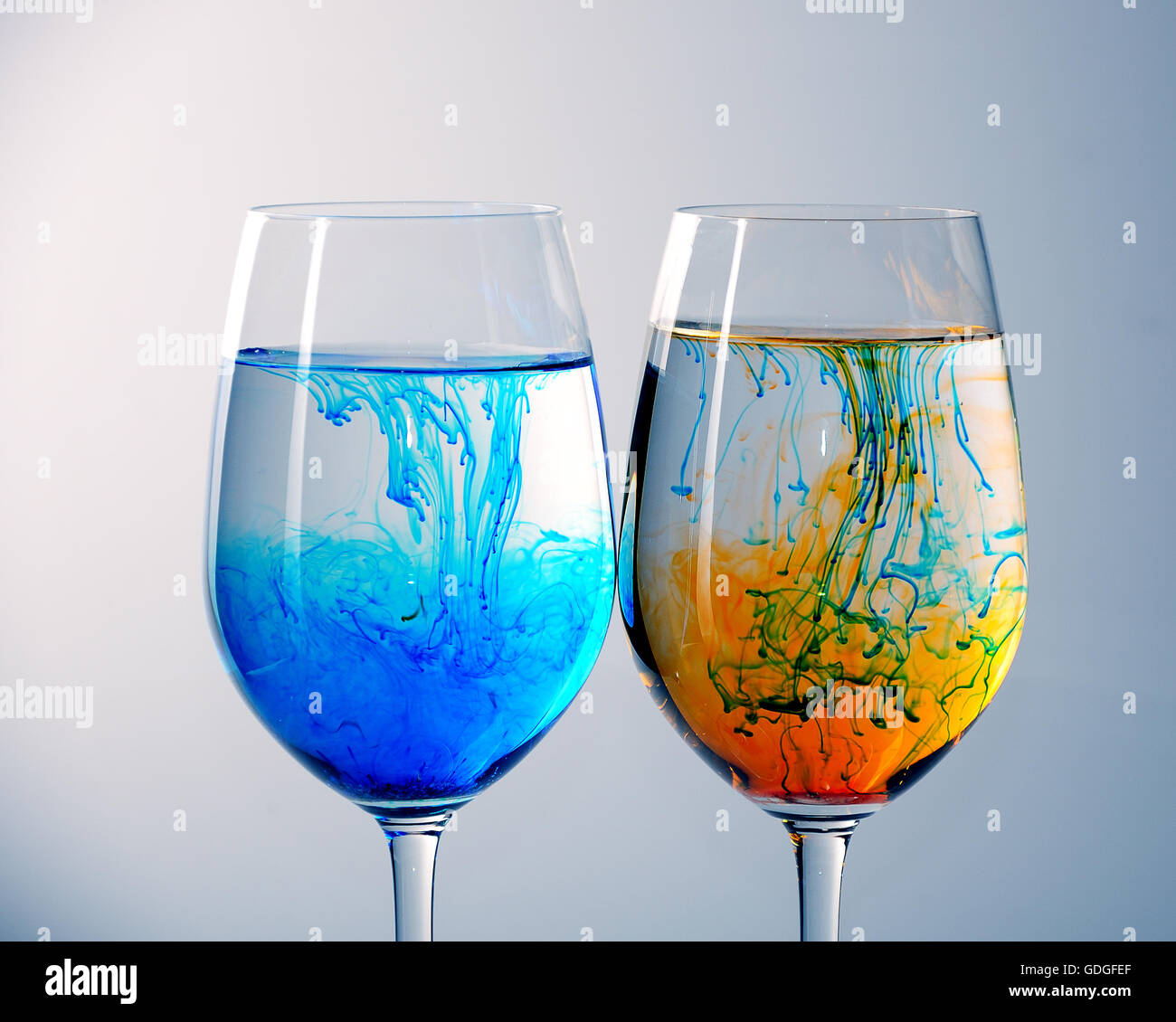 Due bicchieri di vino riempito con acqua e diffondere il rosso, il giallo e il blu inchiostro Foto Stock