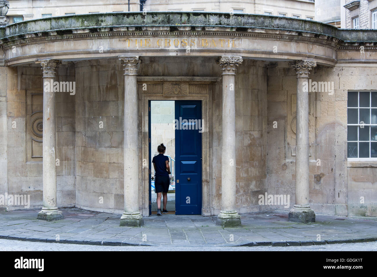 Signora camminando attraverso la porta della croce vasca da bagno. Donna cammina attraverso la porta per la piscina e il centro termale nel Patrimonio Mondiale UNESCO Città di Bath Foto Stock