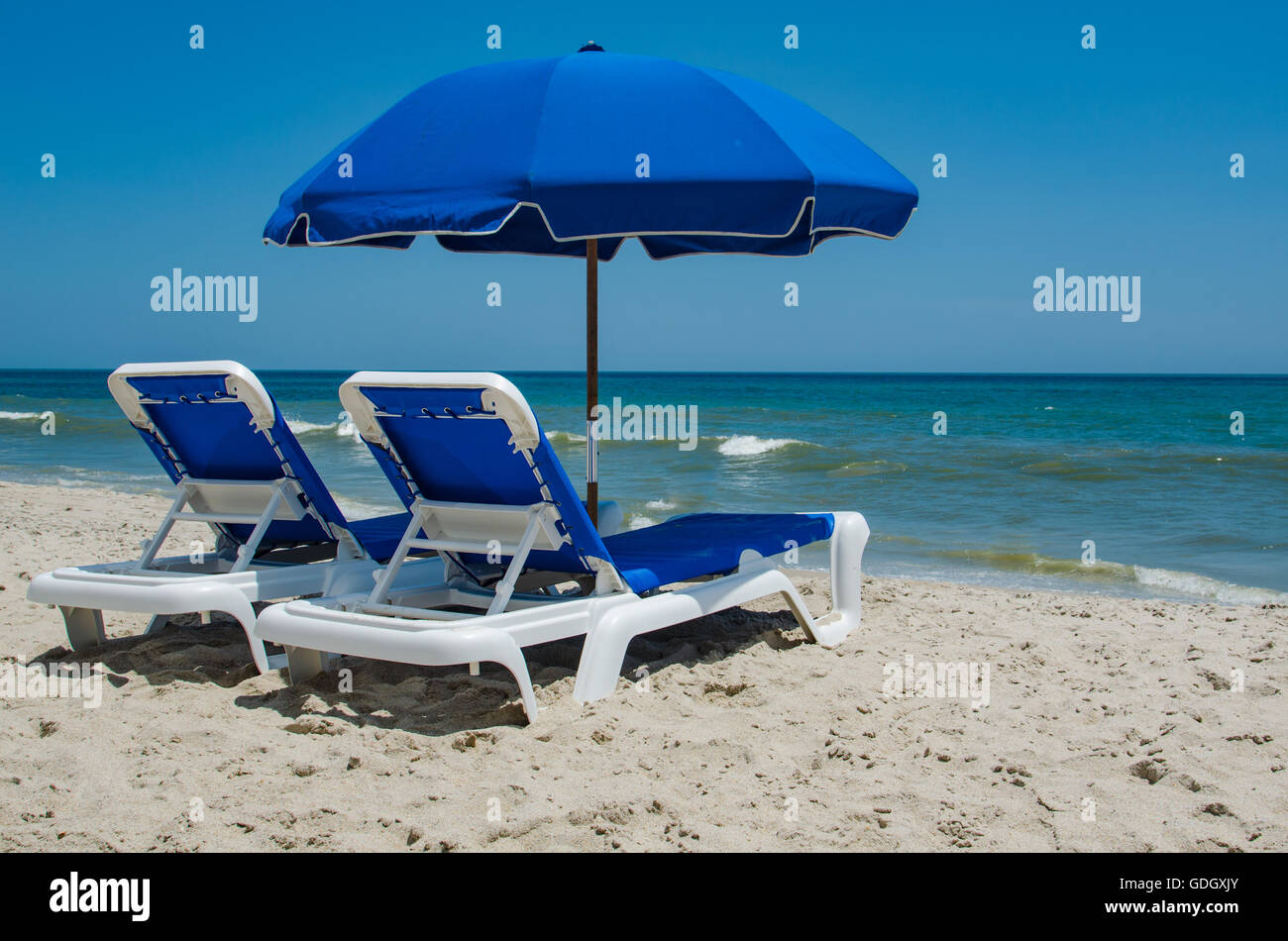 Sedie a sdraio sulla spiaggia contro un cielo blu chiaro Foto Stock