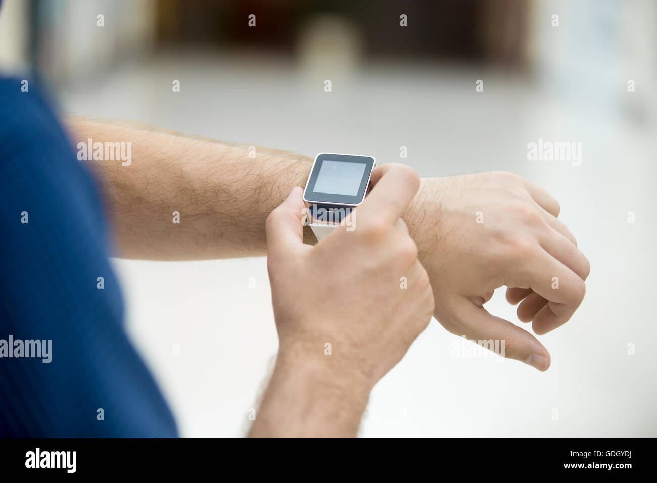 Stretta di mano del giovane toccando il display sul suo orologio intelligente con schermata nera vuota, utilizzando internet, messaggistica, rendendo cal Foto Stock