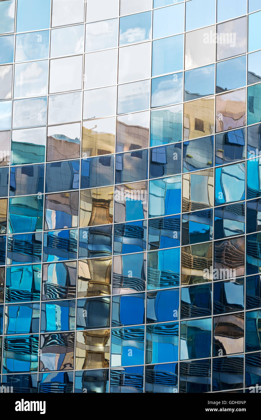 La parete di vetro di un edificio alto e moderno con riflessioni Foto Stock