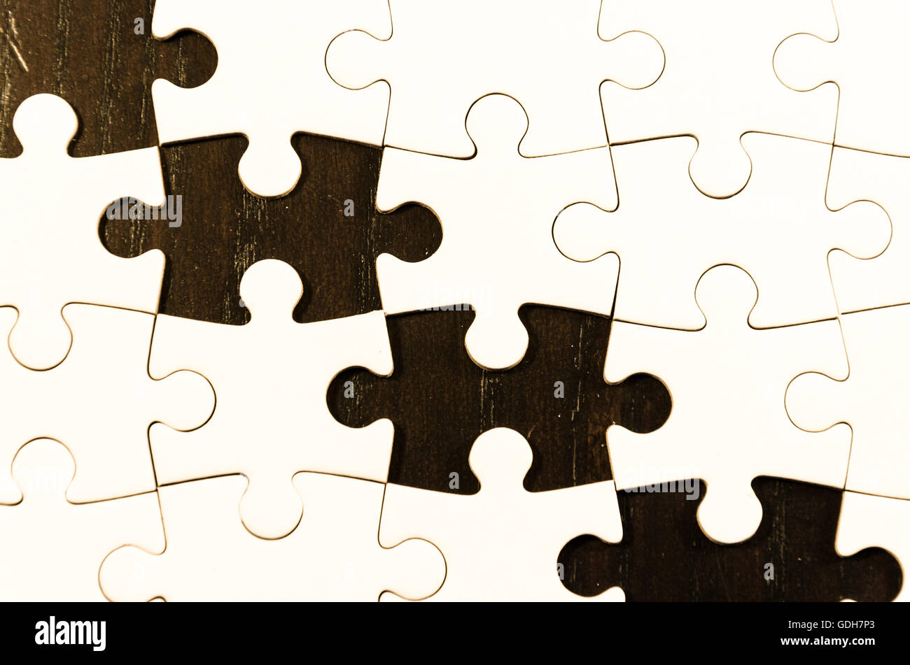 White jigsaw puzzle/white alcune lacune su tavoli in legno nero sfondo, simbolo di problem solving Foto Stock