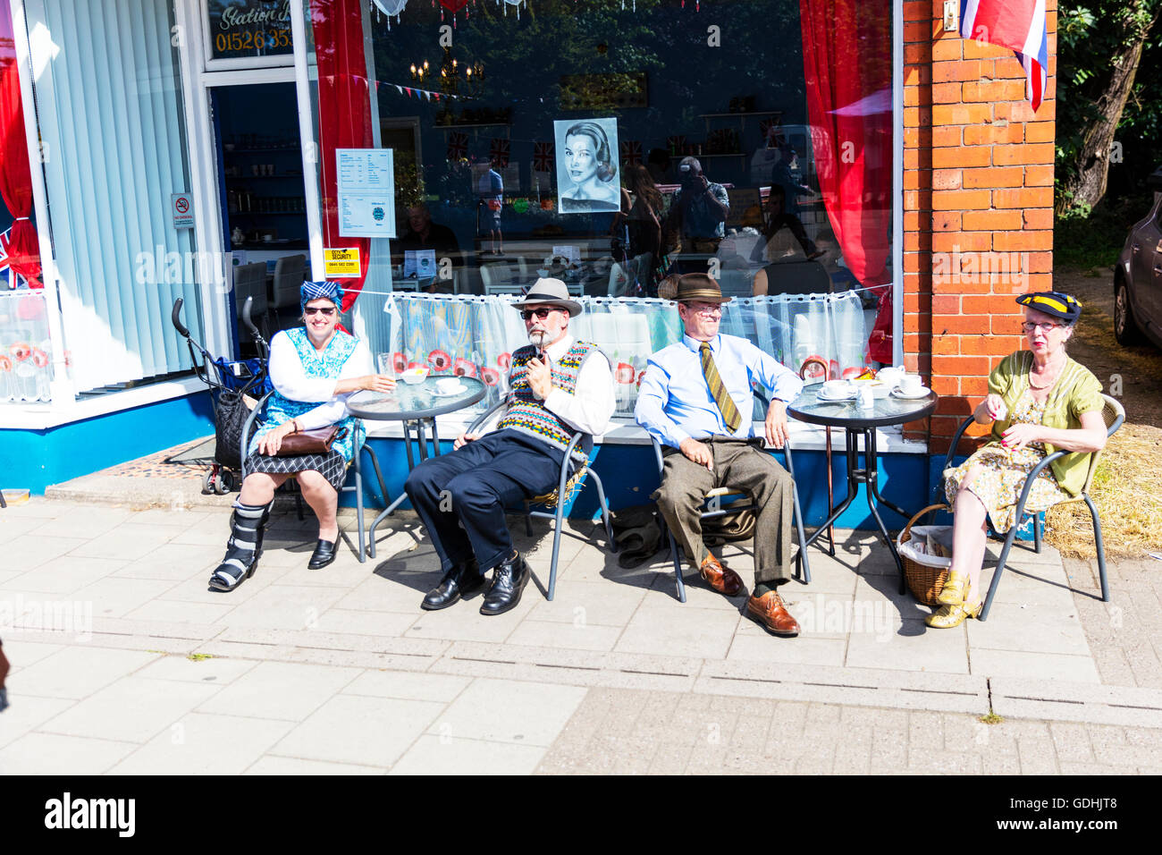 Gustando il tè del pomeriggio al di fuori del caffè sulla strada le coppie seduto a tavola le tabelle di bere il caffè godere di sole estate al fresco REGNO UNITO Inghilterra 1940 look abbigliamento abito indossando tute tuta 1940's Weekend a Woodhall Spa Lincolnshire UK Inghilterra su 17/07/2016 più grande del Regno Unito 1940 weekend Persone WW1 Guerra Mondiale 1 era veterans in abito tradizionale uniforme di uniformi e costumi. Un enorme evento vintage come il sole attira le folle di revel in un giorno di vintage musica, danza, moda, cimeli, intrattenimento vintage rievocazioni Credito: Tommy (Louth)/Alamy Live News Foto Stock