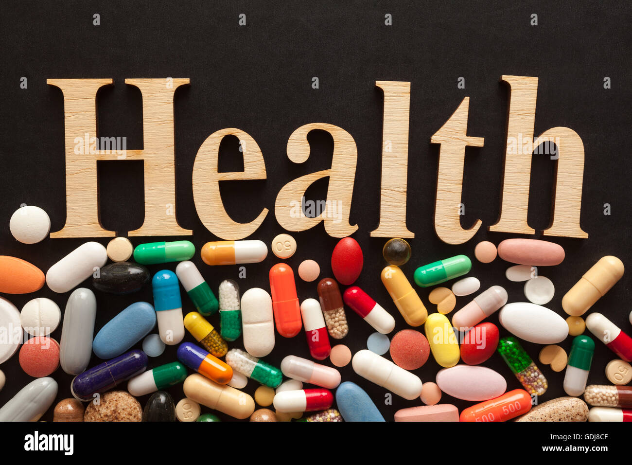 Parola salute con lettere in legno su pillole colorate Foto Stock