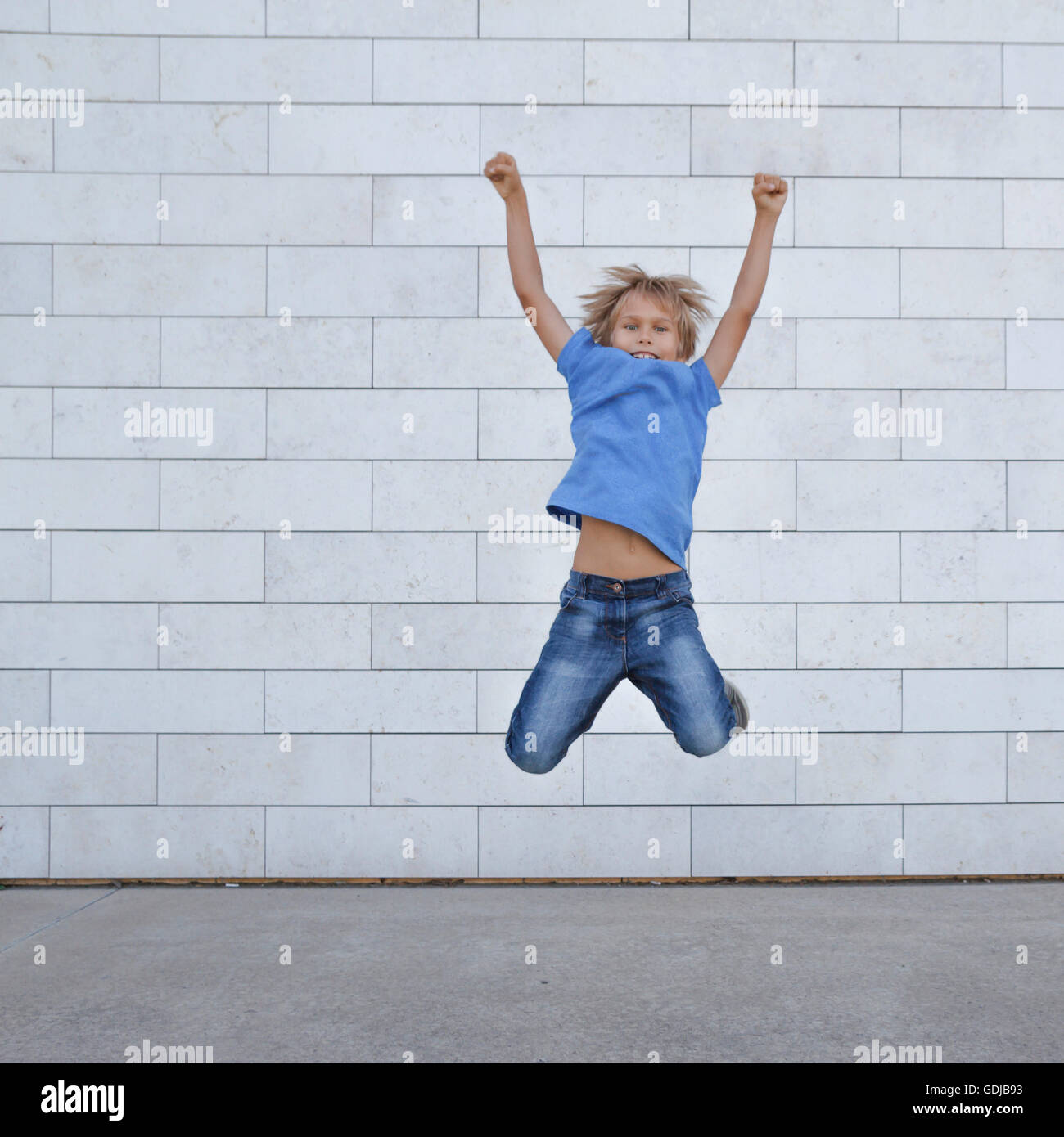 Happy little boy jumping in città. Persone, infanzia, la felicità, la libertà, la nozione di movimento Foto Stock