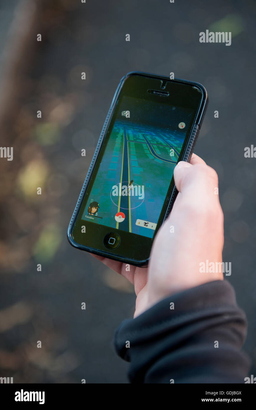 Adolescente utilizzando un iPhone per riprodurre la realtà aumentata gioco Pokemon Go Foto Stock