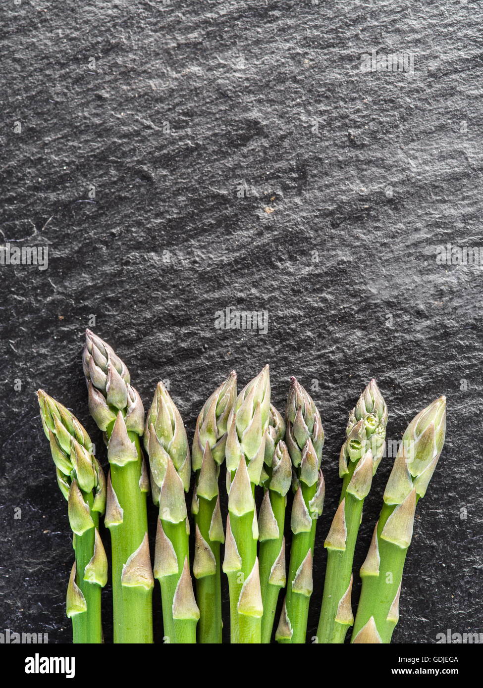 Green giovani germogli di asparagi su sfondo nero. Foto Stock