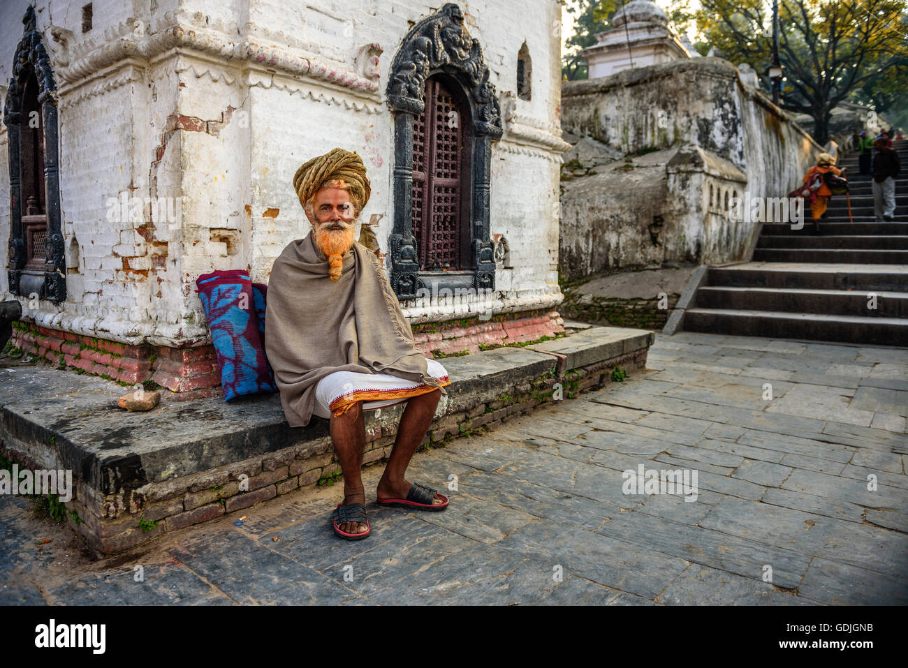 Sadhu errante baba (uomo santo) con i tradizionali lunghi capelli in un antico tempio di Pashupatinath Foto Stock