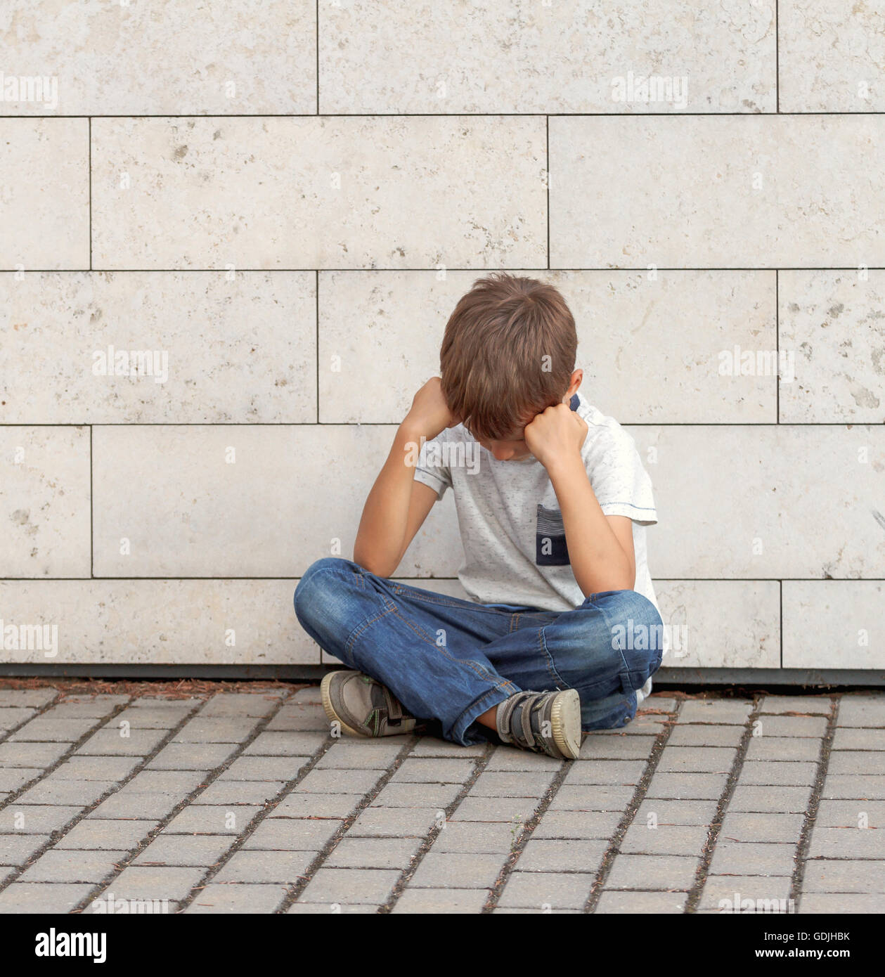 Triste, solitario, infelice, deluso bambino seduto da solo sulla terra.  Ragazzo tenendo la sua testa, guardare in basso. Per esterno Foto stock -  Alamy