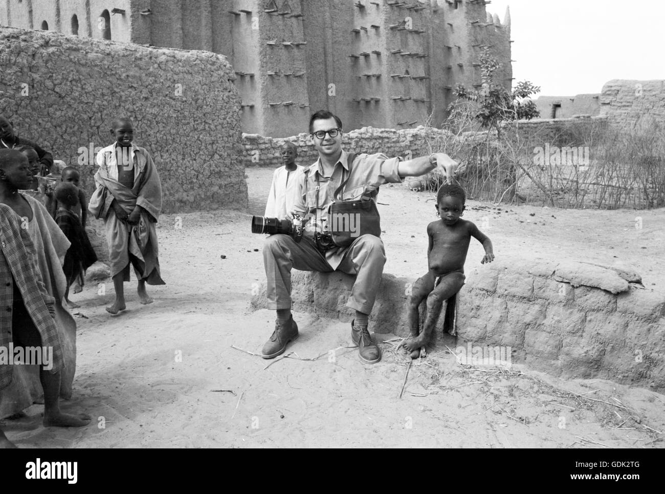 Fotografo Phillip Harrington interagendo con gli abitanti di un villaggio presso la Grande Moschea di Djenne, 1959 Foto Stock