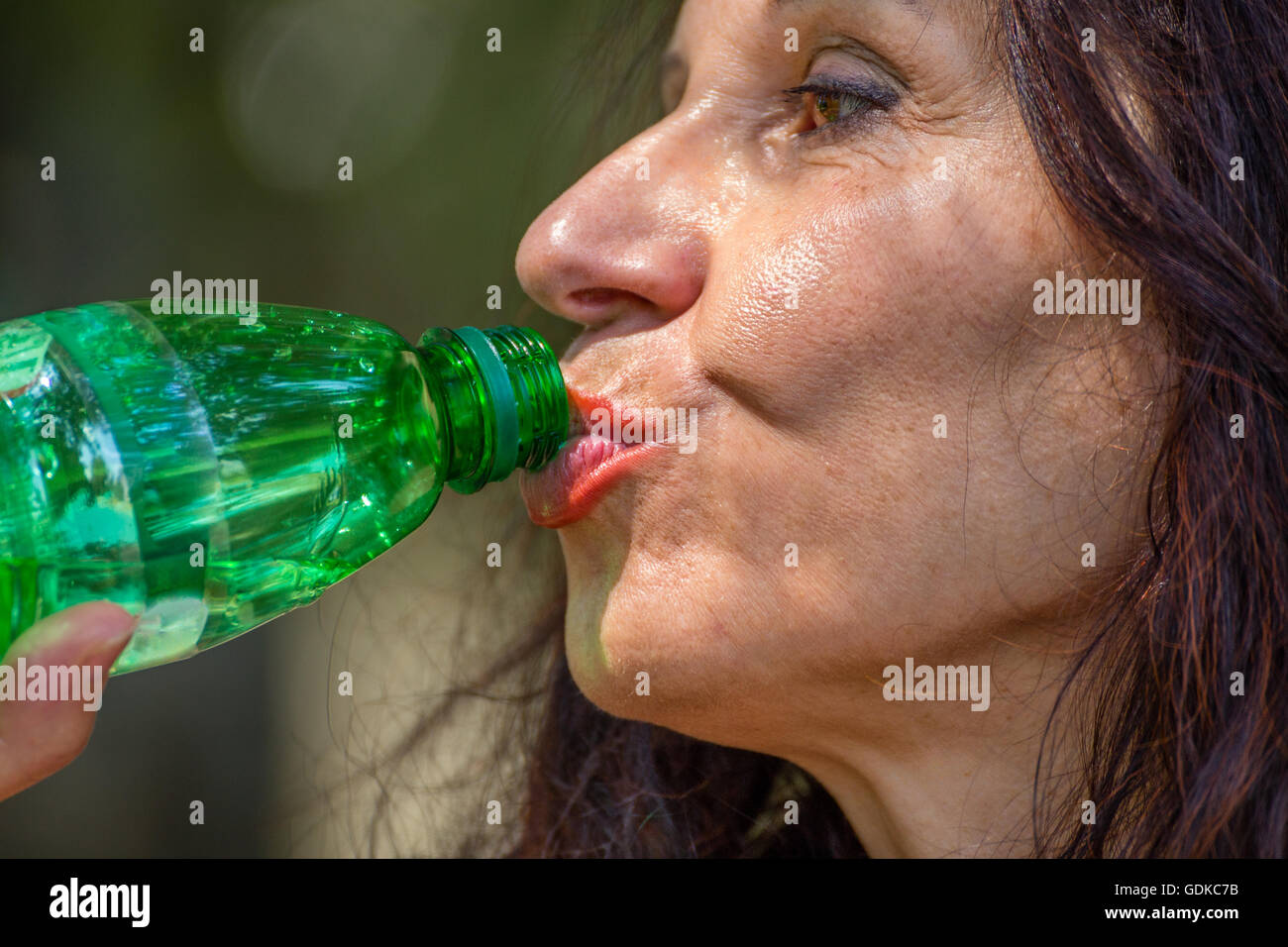 Close up menopausa la donna matura acqua potabile da una bottiglia di plastica Foto Stock