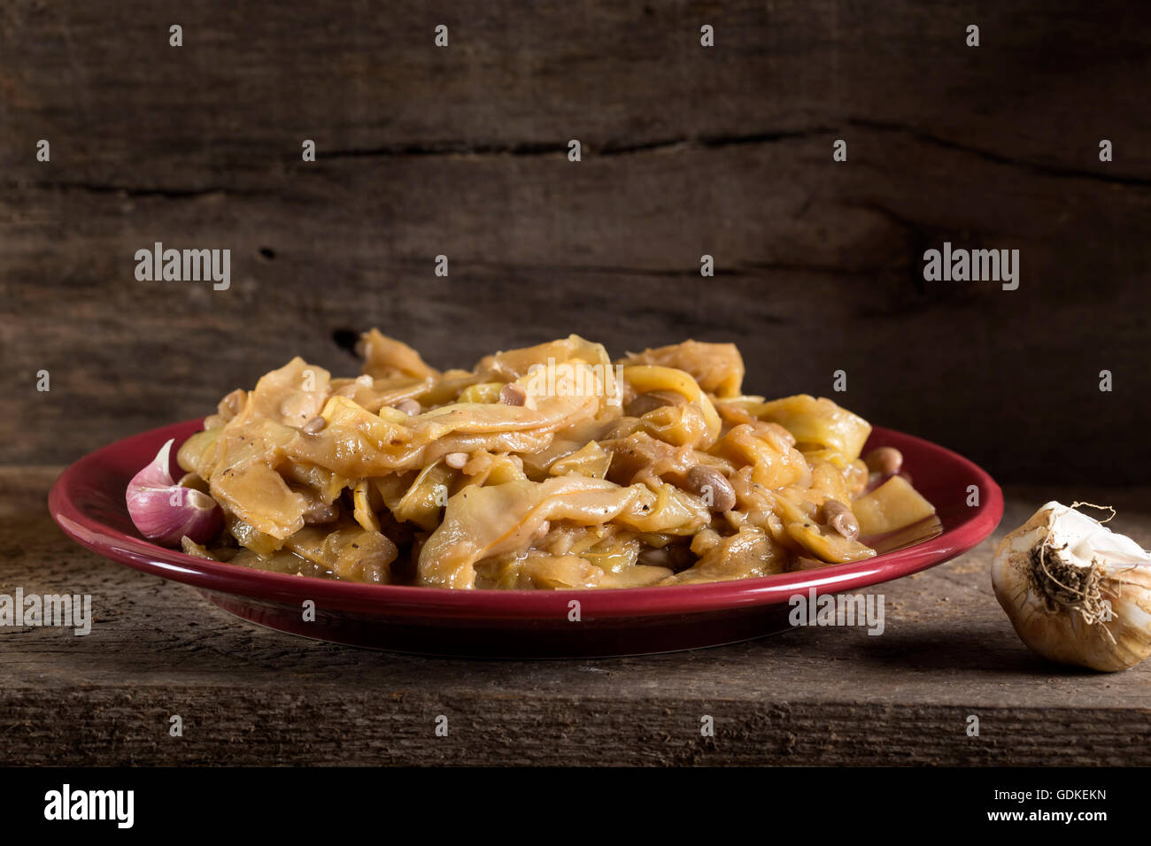 Ampio cotti Fagioli baccelli con aglio sulla targhetta rossa in legno sfondo rustico Foto Stock