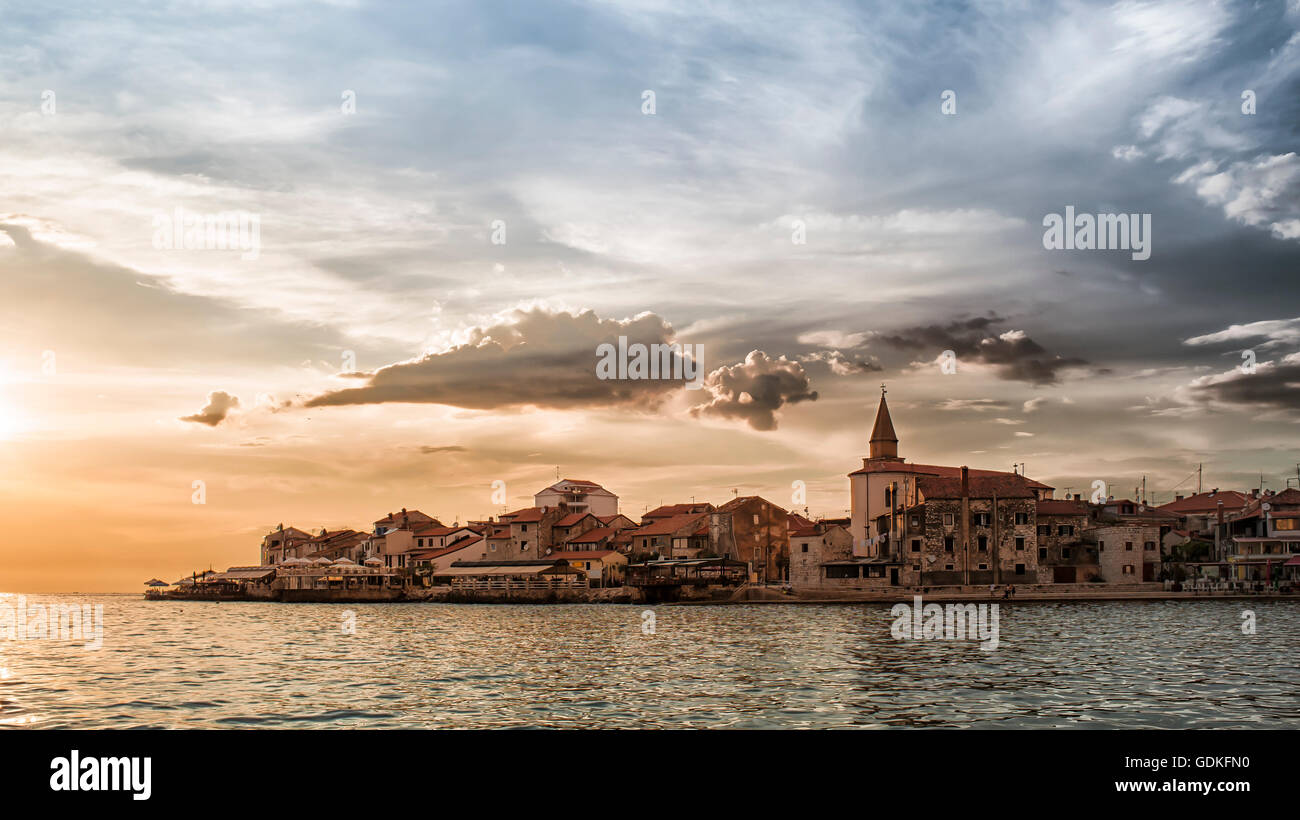 La costa e il promontorio di Umag Croazia al tramonto con il cielo in tempesta Foto Stock