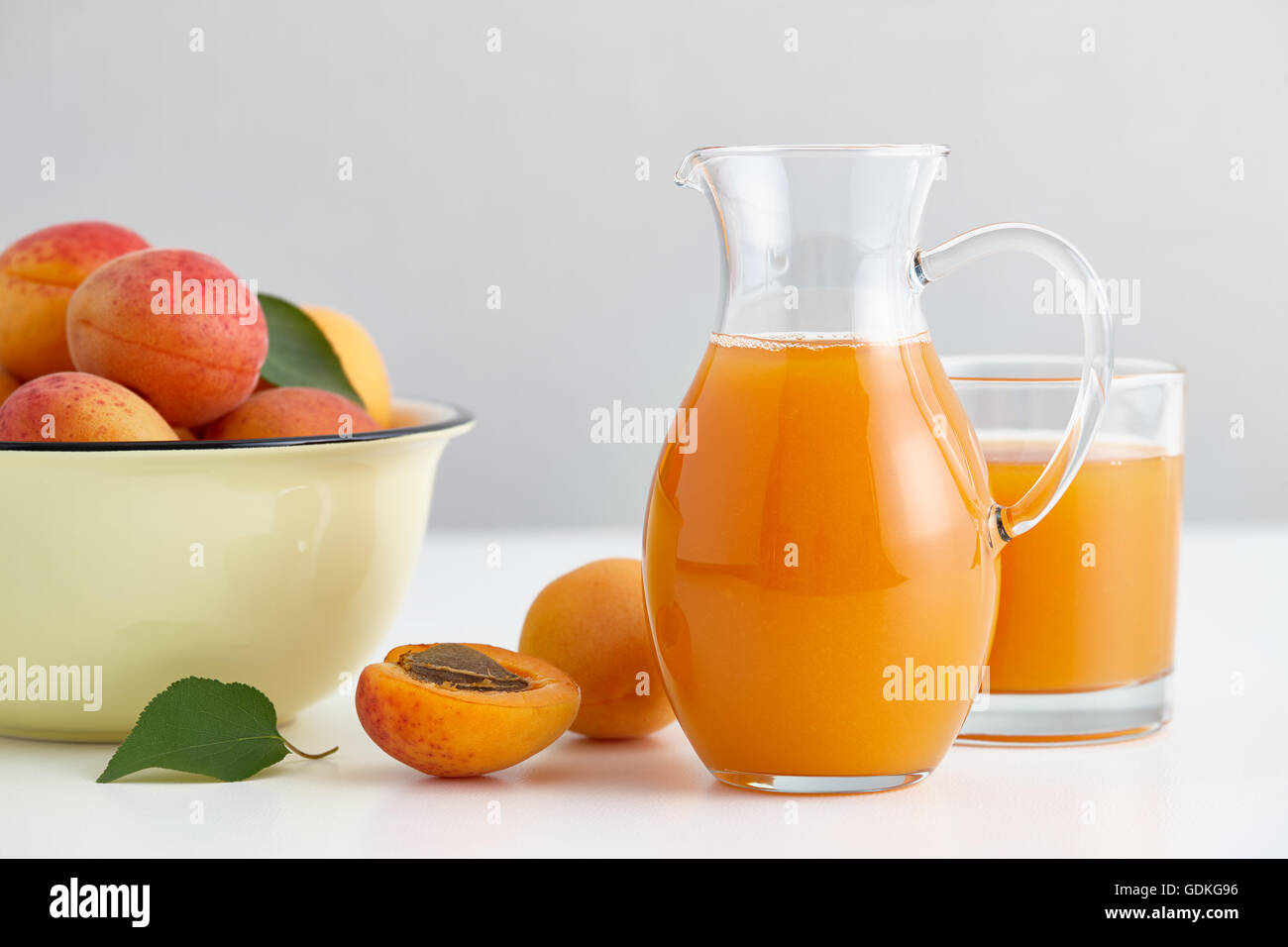 Caraffa di vetro con del succo di frutta fresco e albicocche mature ciotola Foto Stock