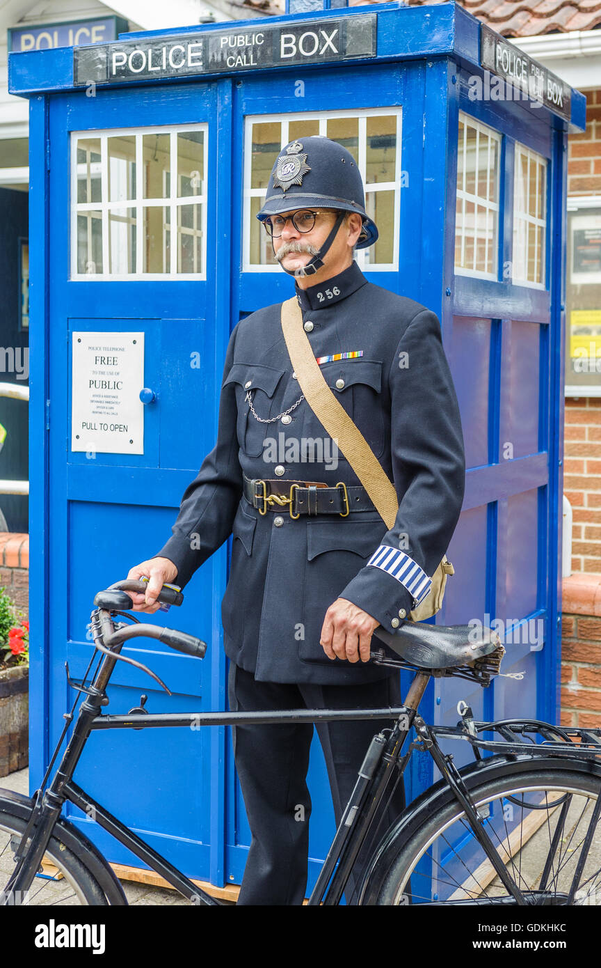 Woodhall Spa 1940 Festival - poliziotto vestito negli anni Quaranta era uniforme da un tradizionale telefono polizia box Foto Stock