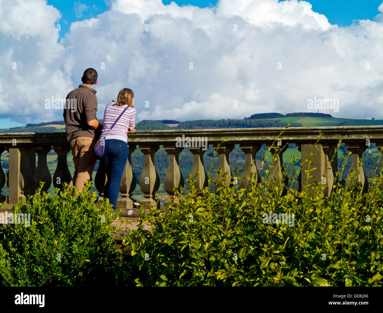 Giovane appoggiato su di una balaustra in pietra e godendo della vista sulla campagna Foto Stock