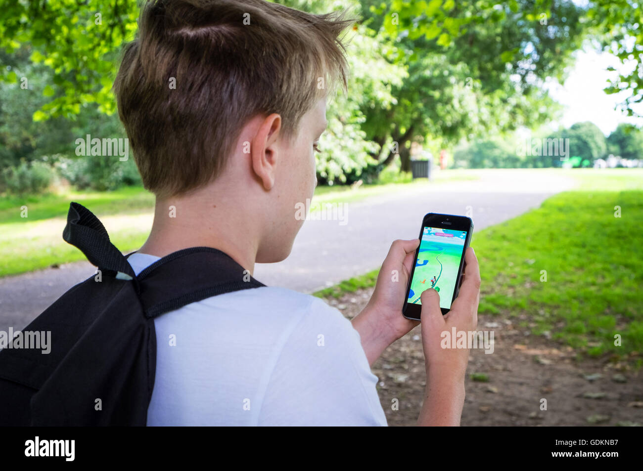 Un ragazzo nel parco giocando il nuovo Pokemon gioco vai sul suo telefono cellulare Foto Stock