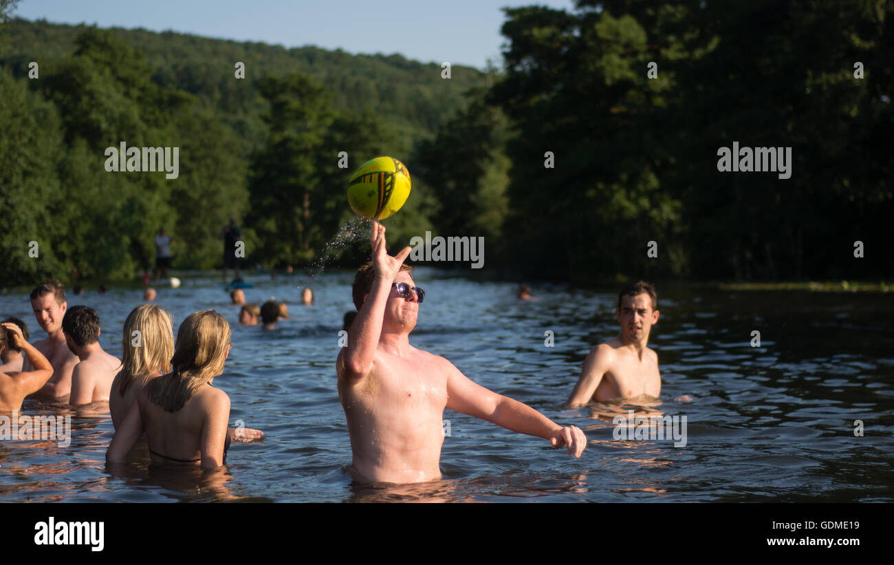 Uomo di gettare la sfera nel fiume Avon, con nuotatori. Centinaia accorrono per Warleigh Weir a 3 miglia da bagno su il giorno più caldo dell'anno Foto Stock