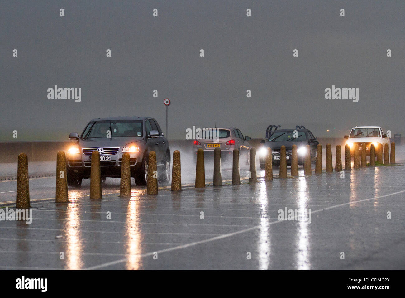 Southport Merseyside, Regno Unito. Il 20 luglio, 2016. Heavy Rain, thundery docce e cieli bui oltre la strada costiera come pendolari negoziare allagato strade e sopportare grandine sul lungomare esplanade. Forti piogge e inondazioni che causano un eccessivo spray che colpisce la visibilità. Credito: MediaWorldImages/Alamy Live News Foto Stock