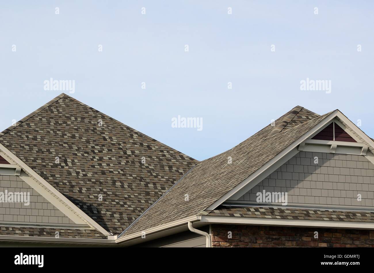 Scandole di asfalto su un tetto dell'anca con timpano abbaini su una casa residenziale Foto Stock