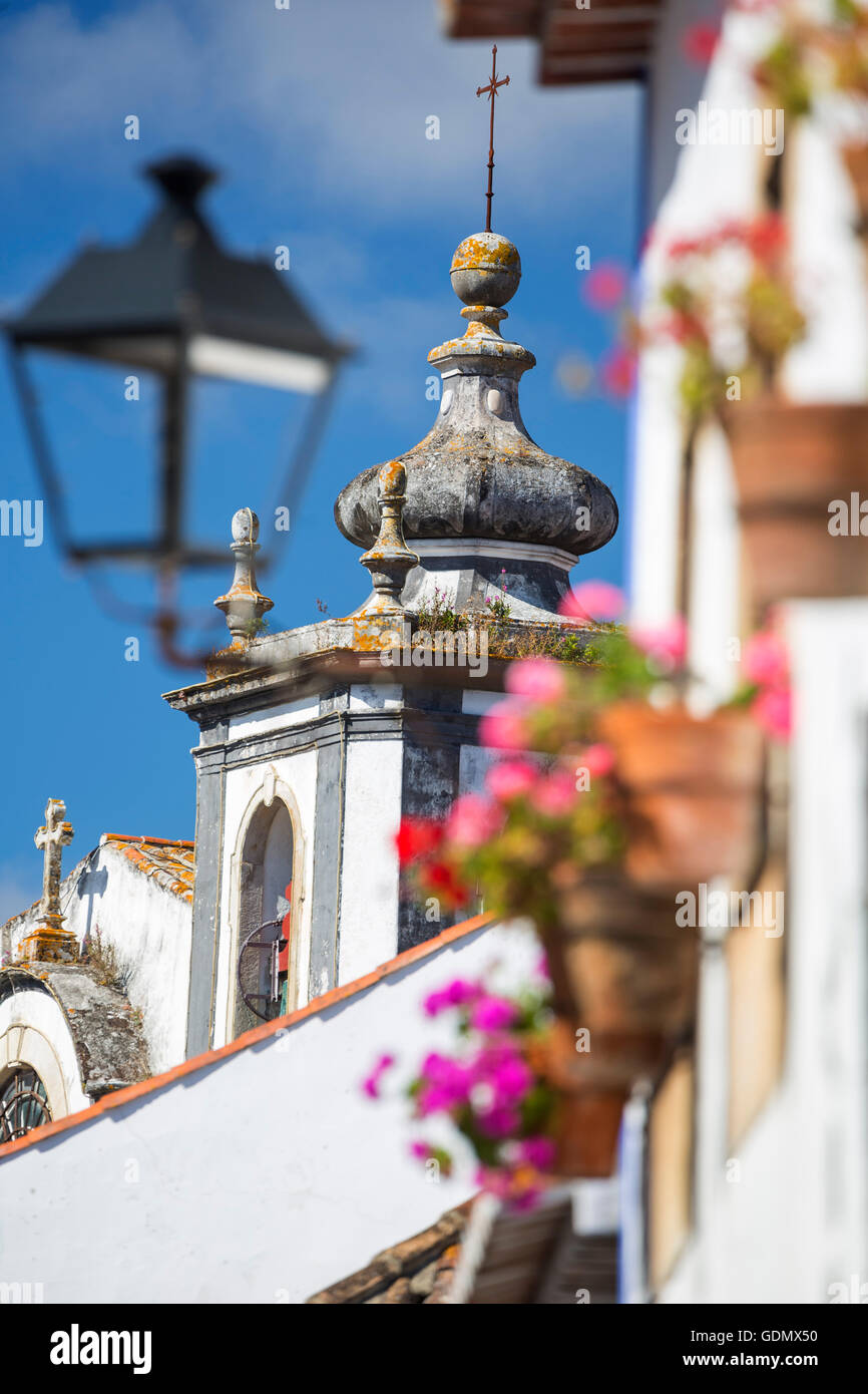 Pittoresche facciate con primule e vasi di fiori, chiesa torre, piccola e pittoresca cittadina di Obidos, Obidos, Distretto di Leiria, Foto Stock