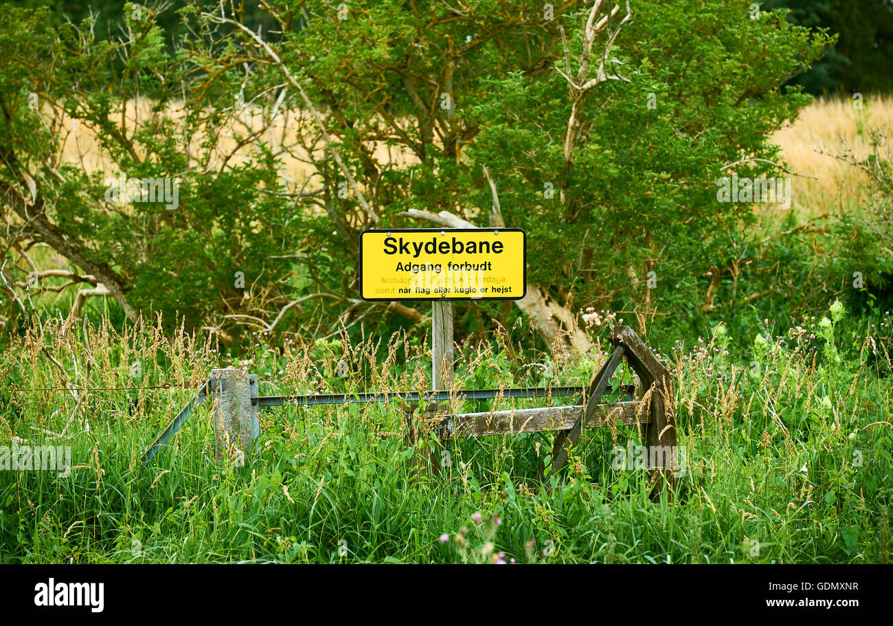Cartello giallo in danese dicendo - Tiro a segno, nessun ingresso, quando la bandiera o la sfera è sollevata - in piedi presso le forze armate exercis Foto Stock