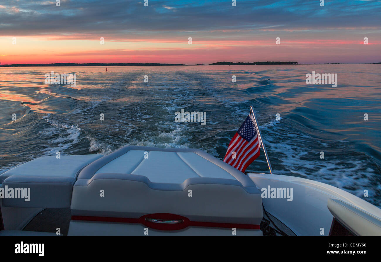 Gite in barca al tramonto con la poppa, bandiera americana e l'acqua. Foto Stock