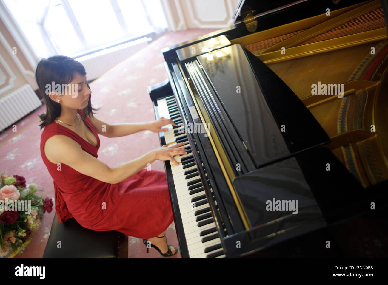 La donna in un abito rosso riproduzione di un pianoforte a coda Foto Stock