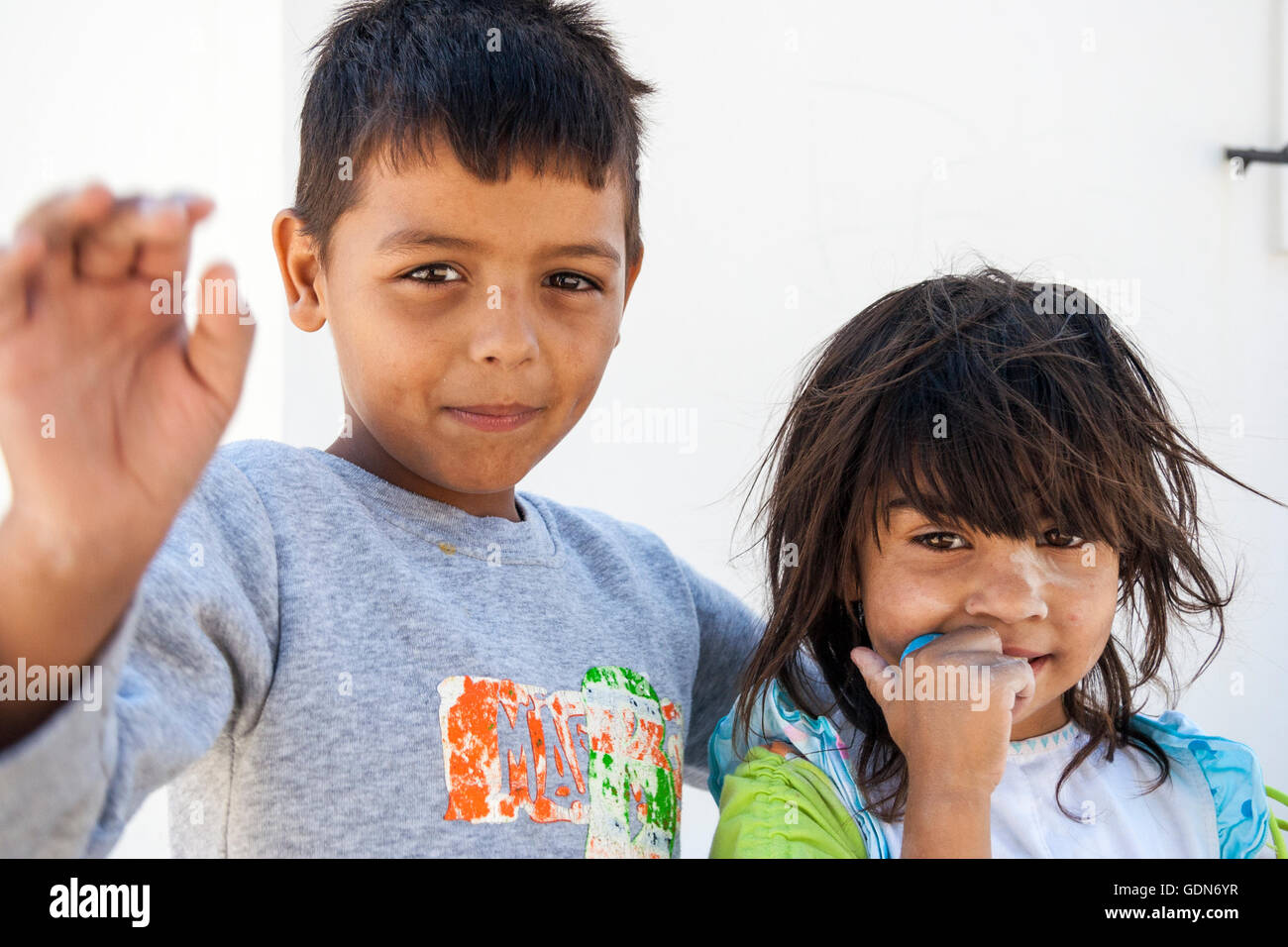 Le isole greche, Santorini. Due bambini, fratello e sorella, un ragazzo e una ragazza, 8-10 anni. Testa e spalle, guardando il viewer, ragazzo agitando nervosamente. Foto Stock